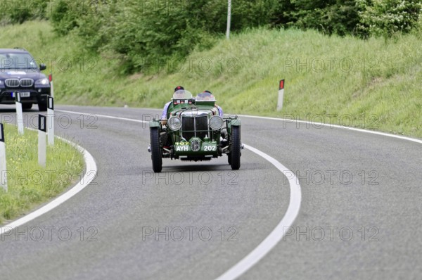 Green vintage car drives on winding country road, lined with green landscape, vintage car, car