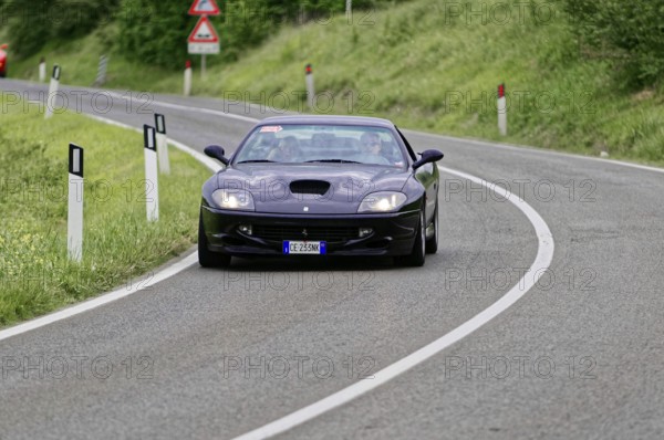 Dark blue sports car on a winding road in a rural setting, classic car, car race, Mille Miglia,