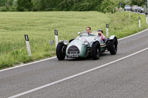 Grey classic car on a country road surrounded by green fields and trees, classic car, car race,
