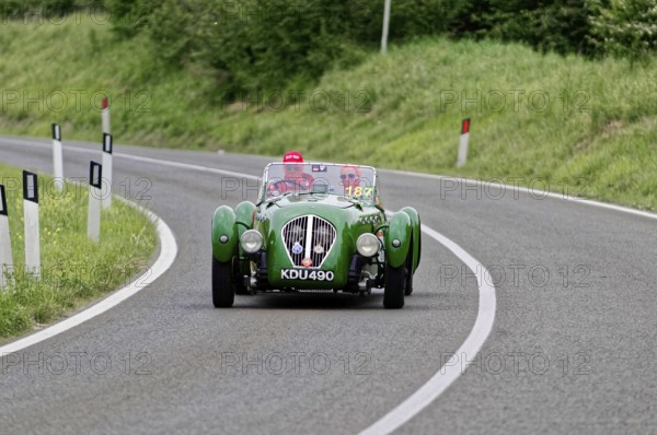 Green classic car driving on a winding country road, classic car, car race, Mille Miglia, 1000