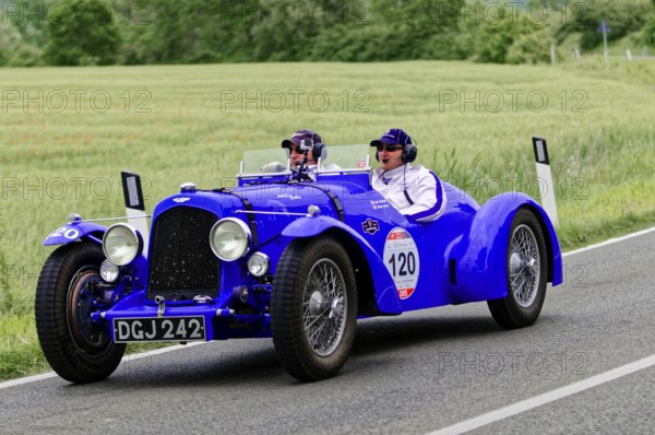 Two people in a blue vintage car on a country road, vintage car, car race, Mille Miglia, 1000