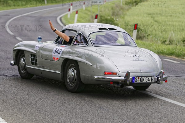 Silver retro sports car turns off on a winding road, classic car, car racing, Mille Miglia, 1000