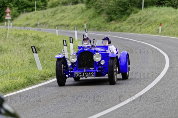 Blue vintage racing car with two people on a country road, classic car, car race, Mille Miglia,
