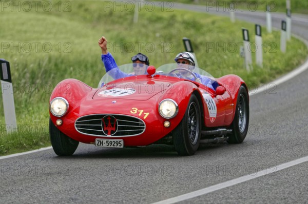 Two people driving in a red Maserati classic car on a winding country road, classic car, car