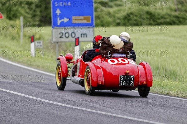 Red classic car on Italian country road towards Siena, classic car, car race, Mille Miglia, 1000