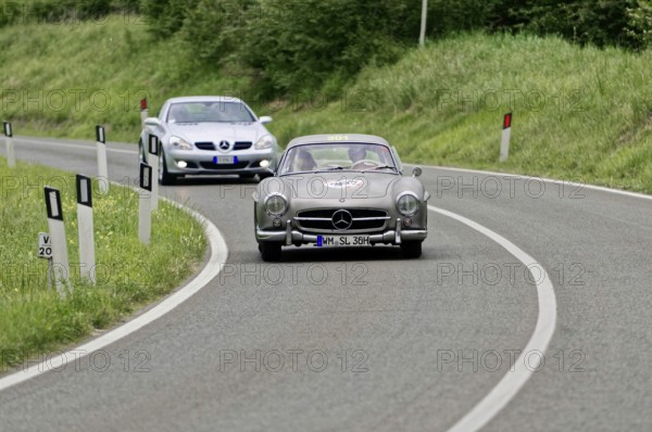 Two classic Mercedes cars driving on a winding country road in a green environment, classic car,