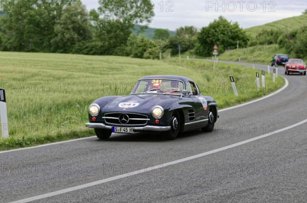 A black Mercedes classic car drives stylishly through the green landscape, classic car, car race,