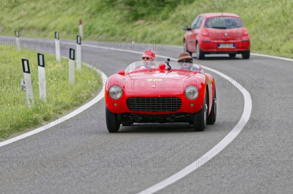 Red Ferrari vintage convertible on a winding country road during a race, vintage car, car race,