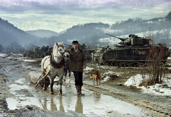 BIH, Tuzla, 01.01.1996 -- A Bosnian farmer pulls his horse past the base camp of American IFOR