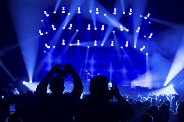 Two concertgoers photograph Sting (civil: Gordon Matthew Thomas Sumner, CBE) live with their mobile