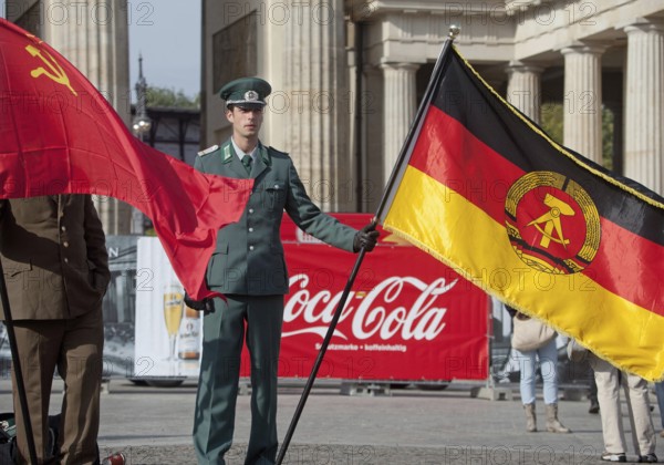 DEU Germany Berlin Actor wearing NVA uniform poses with the GDR flag in front of a Coca-Cola