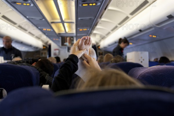 DEU Germany Berlin A passenger stretches her support stocking during an Air Berlin flight to the