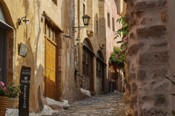 Narrow paved path in the old town with flowering plants and old buildings, Monemvasia, Monemvassia,