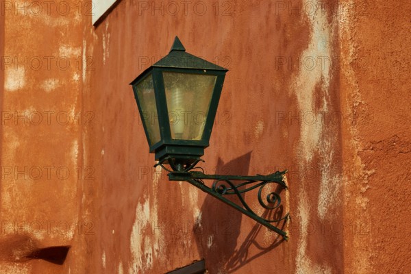 A green lantern hangs on a rust-tinted wall with distinct texture, Monemvasia, Monemvassia,