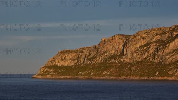 Orhodox church of Hagia Sophia, waterside rocks illuminated by evening sun under clear sky,