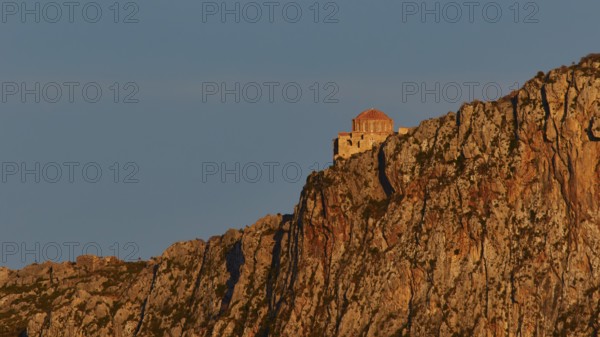 Orhodox church of Hagia Sophia, chapel high on a rock, illuminated in orange evening light,