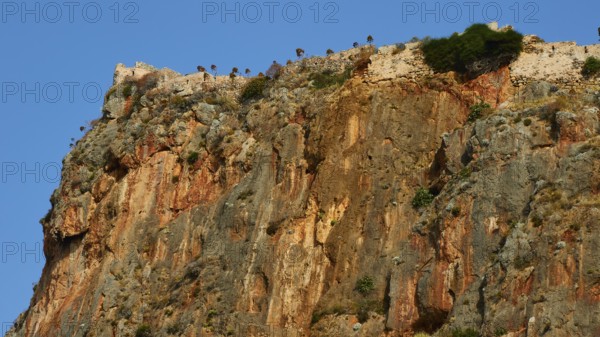 Soft morning light, spectacular cliffs with castle walls and distinct geological layers,