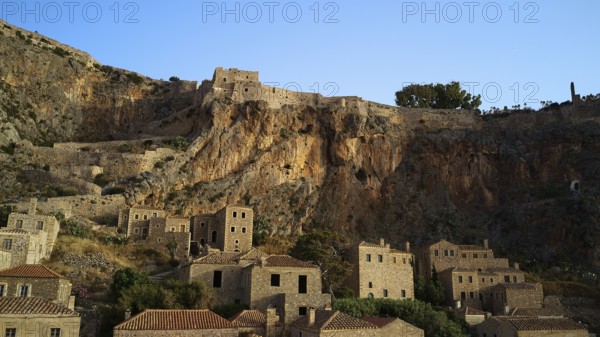 Drone shot, medieval buildings on a rocky cliff overlooking the Mediterranean Sea at sunset,