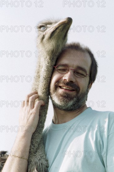 DEU, Mannheim, 22.07.1994 -- ostrich breeder (man, hug, bird ostrich, stroking, affection) -- Â©