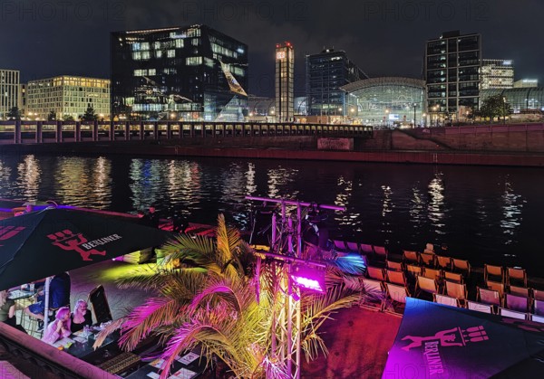 Nightlife on Ludwig-Erhard-Ufer in an outdoor restaurant with the Spree and Berlin Central Station