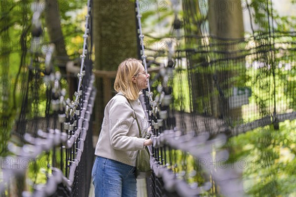 Woman on a rope bridge in the forest, surrounded by trees, Treewalk, Affenberg Salem,