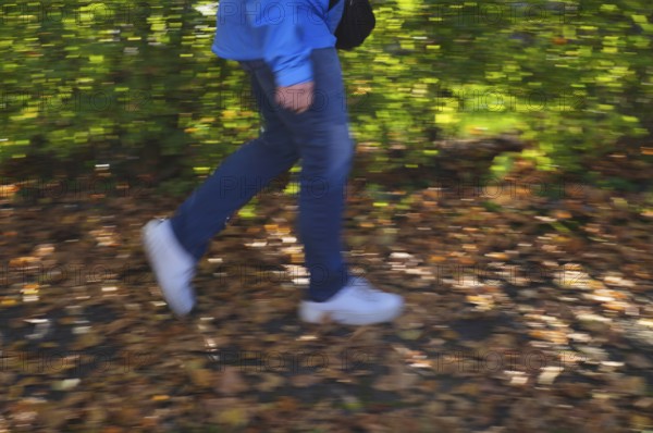 Person, woman, walks on sidewalk full of autumn leaves, autumn, leaves lying on sidewalk, movement