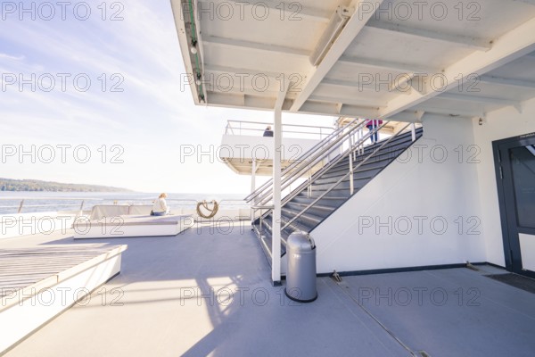 An upper deck of a modern ship with seats and a view of the sea under a blue sky, Schiff Fahrt,