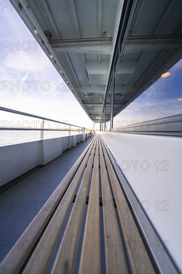 Long ship deck with wooden bench, looking out to sea, with a clear sky above, boat trip, Lake