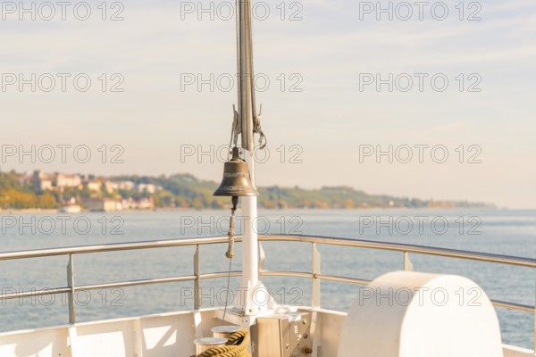View of the water from a ship with a railing and a bell in the foreground, Schiff Fahrt, Lake