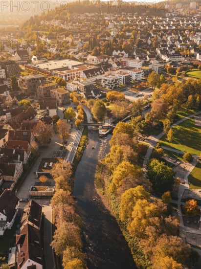 A river flows through an autumnal urban landscape, surrounded by parks and colorful trees, Nagold,