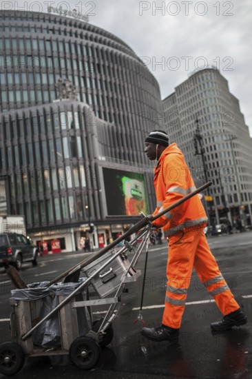 DEU Germany Berlin An employee of Stadtreinigung BSR pushes his handcart across a block of