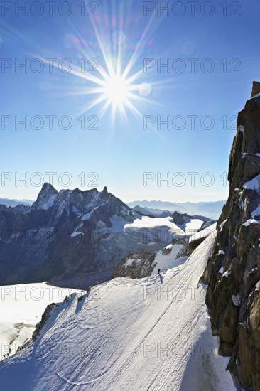 Mountaineers climb over a snow-covered ridge, behind Grandes Jorasses, Aiguille du Midi mountain
