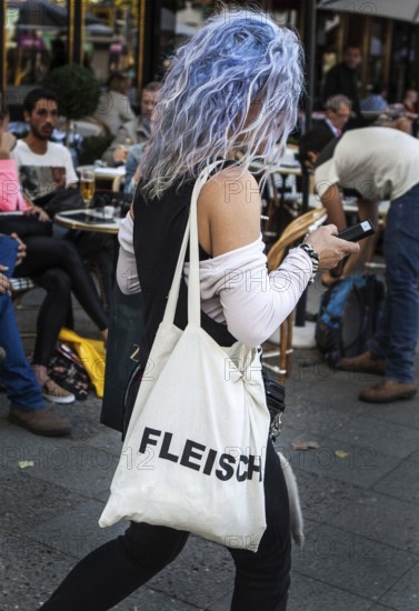 DEU Germany Germany Berlin Woman with blue-dyed hair wears a cloth bag with the inscription Flesh