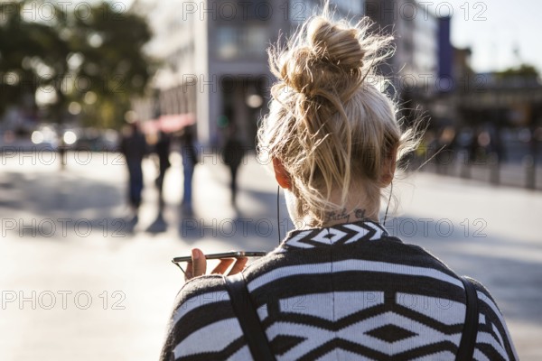 DEU Germany Germany Berlin Woman holds her smartphone while she is telephoning across the square at