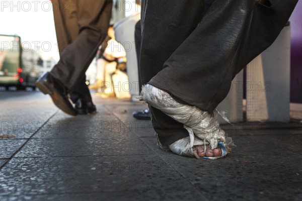 DEU Germany Germany Berlin Homeless person with plastic bag and feet connected to plastic at a bus