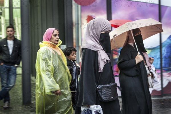 DEU Germany Germany Berlin Women wearing headscarves and face veils walking through the rain on