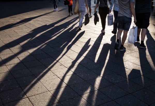 DEU Germany Germany Berlin People with shopping bags cast their shadows on the sidewalk of the cow