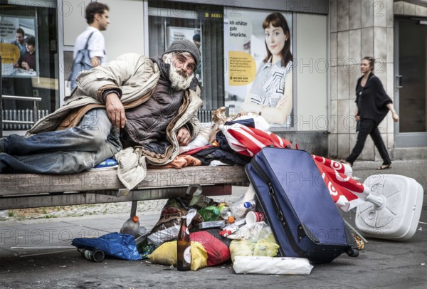 DEU Germany Germany Berlin A homeless person sits on a bench next to his belongings in a square in