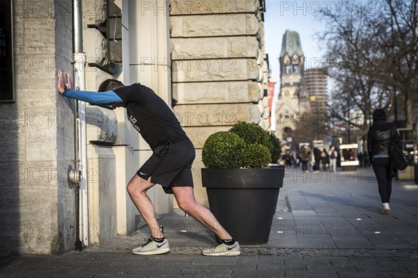DEU Germany Germany Berlin A jogger does gymnastics in front of an Apple shop display case on
