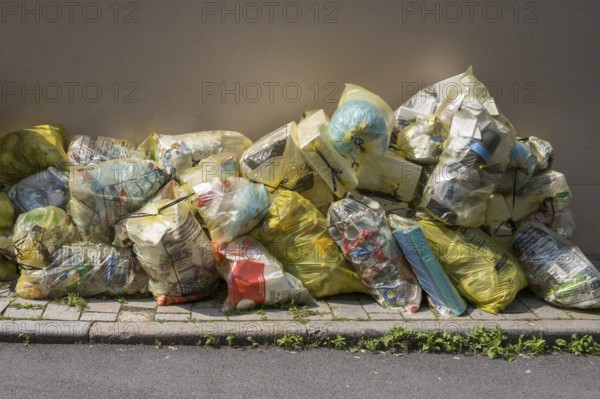 Yellow bags for plastic waste are lying on the side of the road, waste separation, waste disposal,