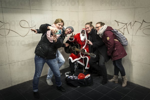 DEU Germany Germany Berlin A dark-skinned singer dressed as Father Christmas plays the guitar in