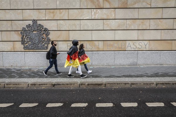 DEU Germany Germany Berlin Two tourists with rain capes in the colours of Germany pass the British