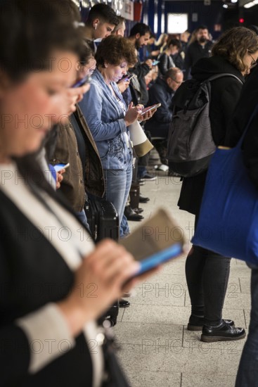 DEU Germany Germany Berlin Passengers look at their mobile phones while waiting for the train at