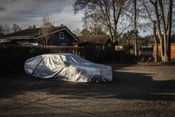DEU Germany Germany Berlin A car, wrapped in a tarpaulin, is parked in a car park next to an