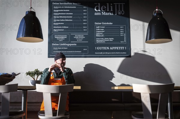 DEU Germany Germany Berlin A man eats a sandwich in a snack bar attached to the Rewe supermarket in