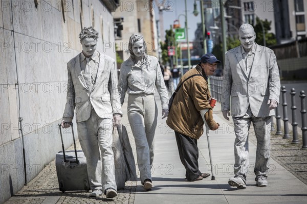 DEU Germany Germany Berlin Three people painted in grey walk along the wall of the Ministry of
