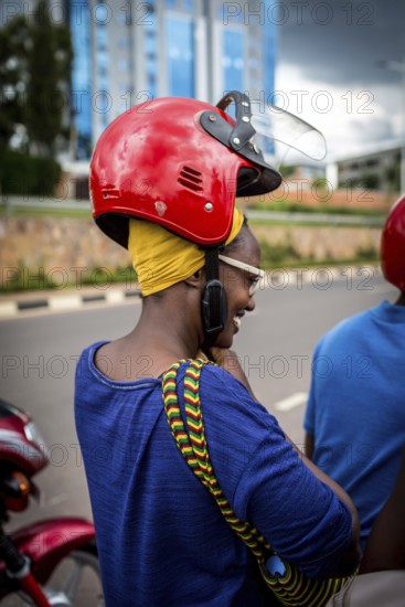 RWA RWANDA RUANDA Kigali A woman with a high hairstyle locks her helmet in front of taking a taxi