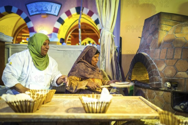 Egypt Hurghada Two elderly Egyptian women bake bread during an evening promotional event for