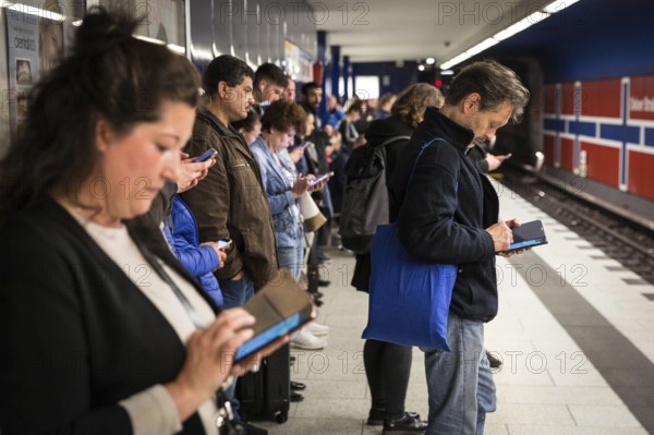 DEU Germany Germany Berlin Passengers look at their mobile phones while waiting for the train at