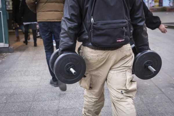 DEU Germany Germany Berlin A man carries two dumbbells in his hands on his way to the underground